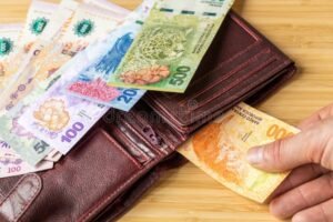 manos con monedas y billetes argentinos