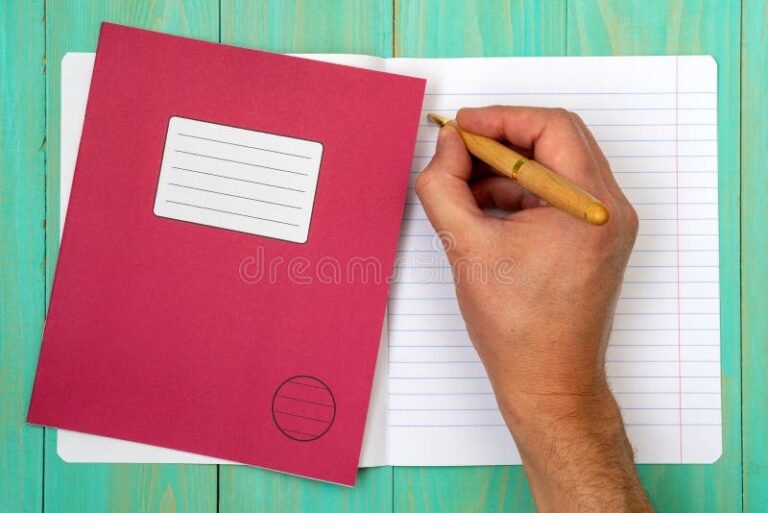 manos escribiendo en cuaderno escolar abierto