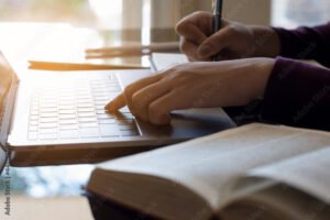 persona escribiendo con libro y computadora