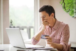 persona usando laptop con tarjeta bancaria